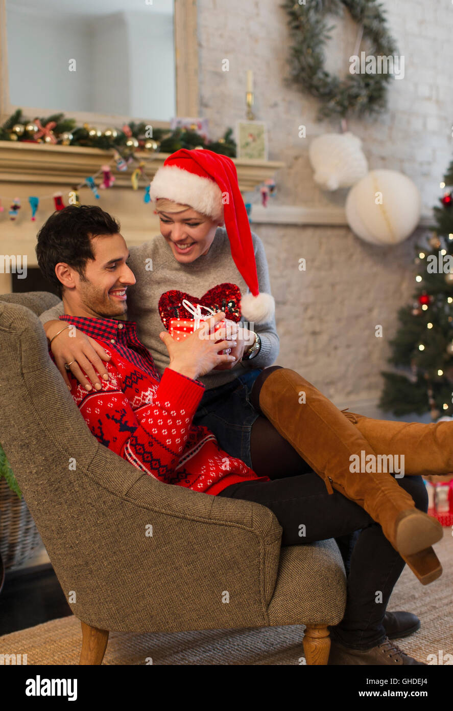 Affettuosa giovane di aprire i regali di Natale in salotto Foto Stock