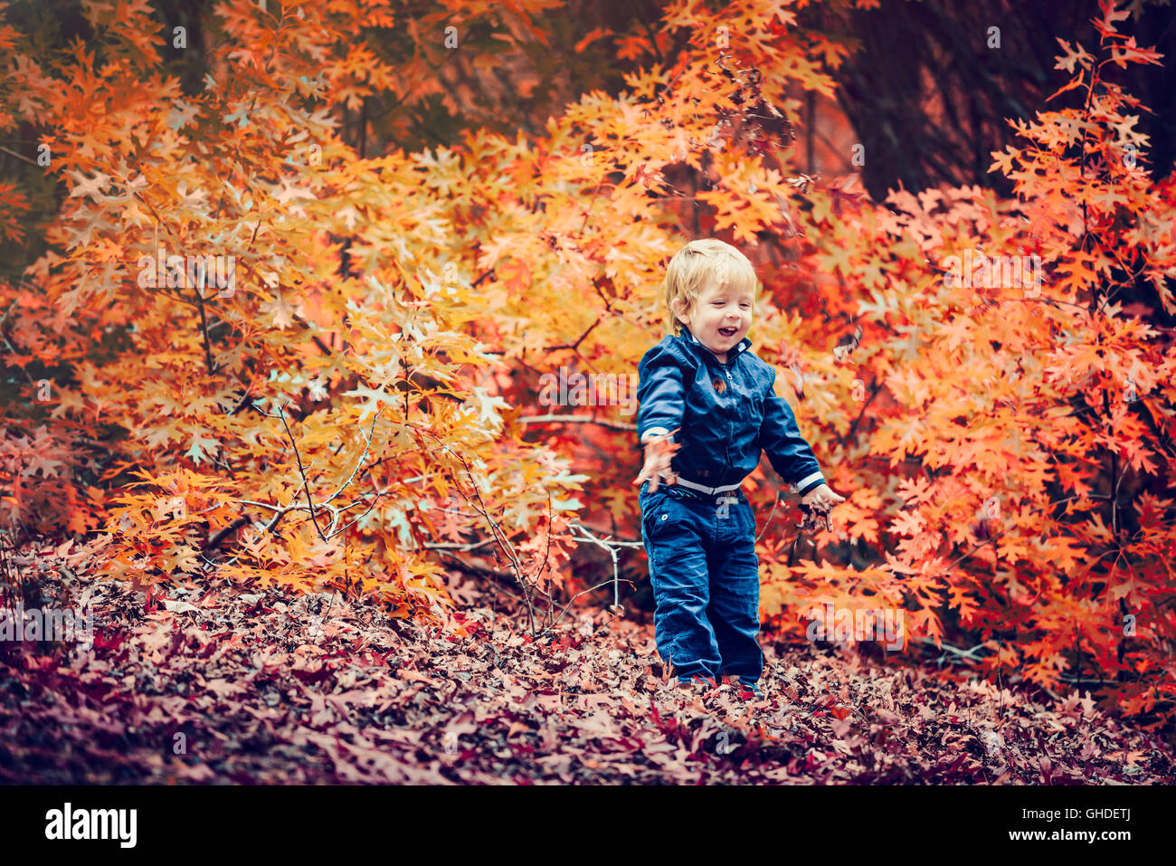 Sorridenti kid giocando con foglie di autunno nel parco.Color-tonificante applicato Foto Stock