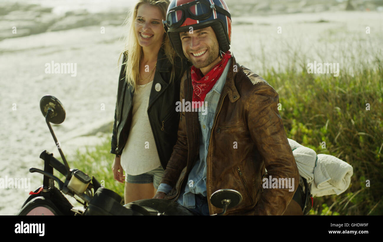 Ritratto sorridente coppia giovane in motocicletta sulla spiaggia Foto Stock