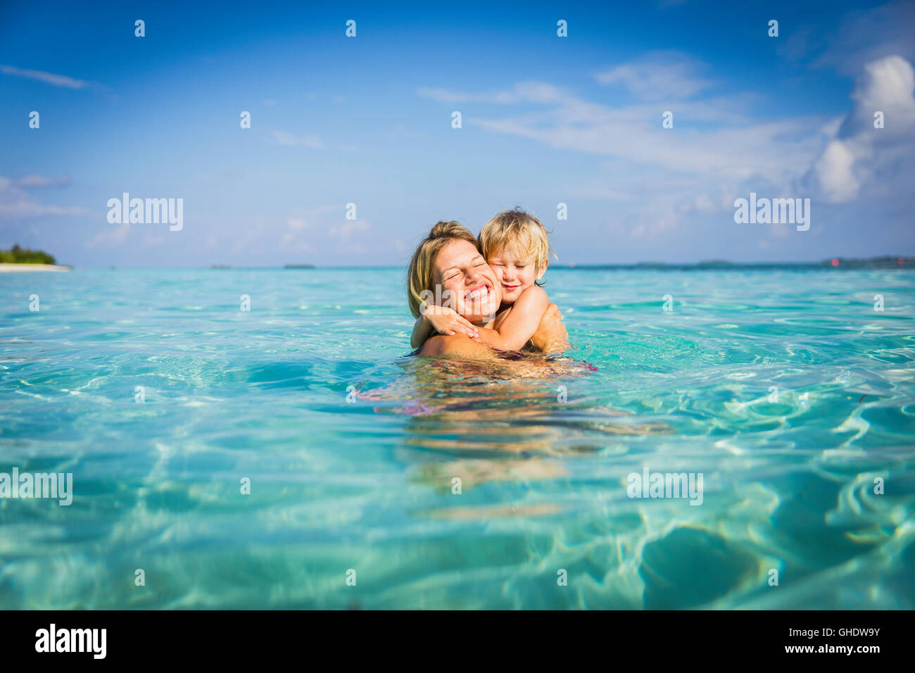 Entusiastici abbracci madre figlio nell'oceano tropicale Foto Stock