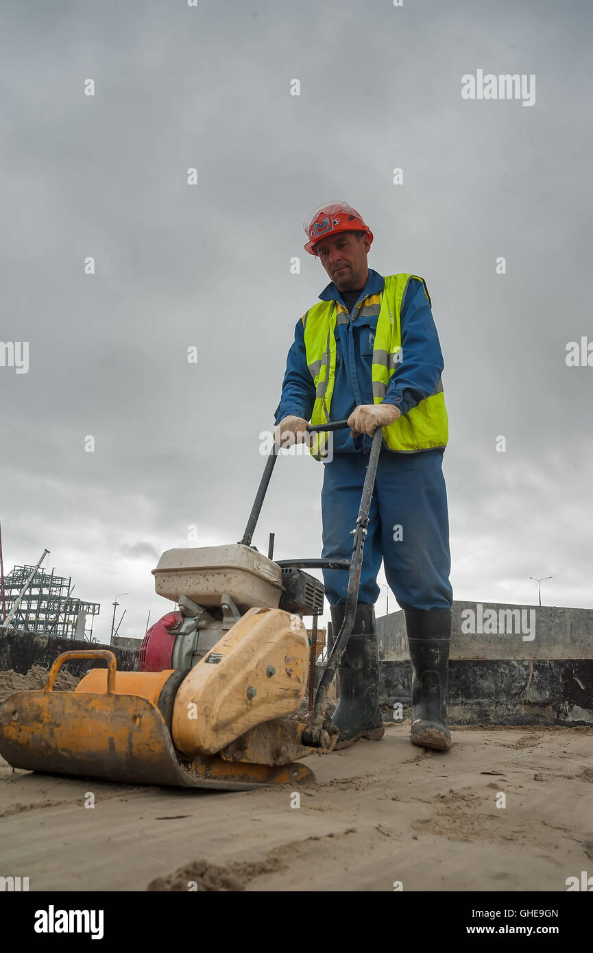 Builder lavoratore con piastra di vibrazione Foto Stock