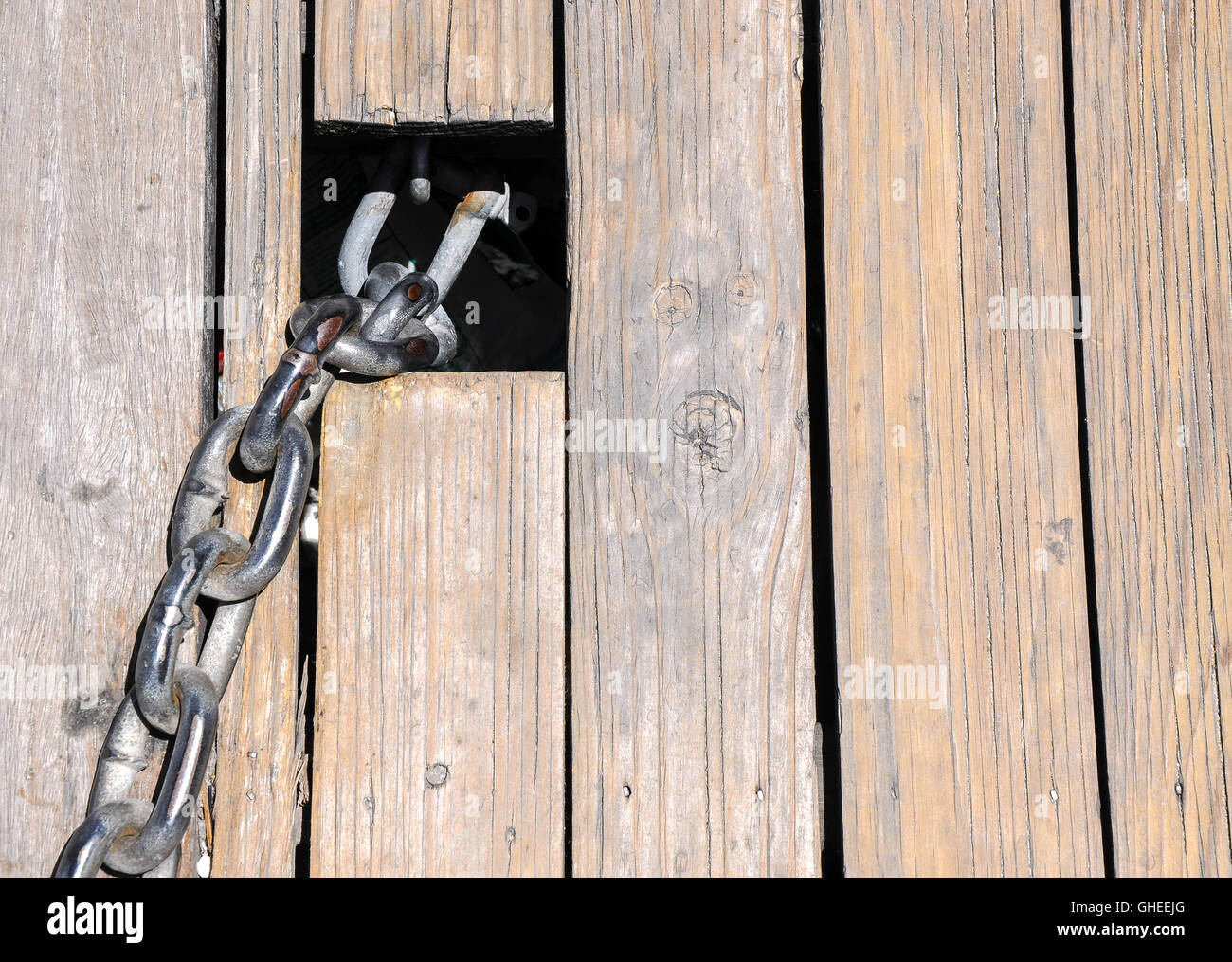 Abstract closeup di weathered tavole di legno e tesa la catena di metallo link in uscita intaglio quadrato. Foto Stock