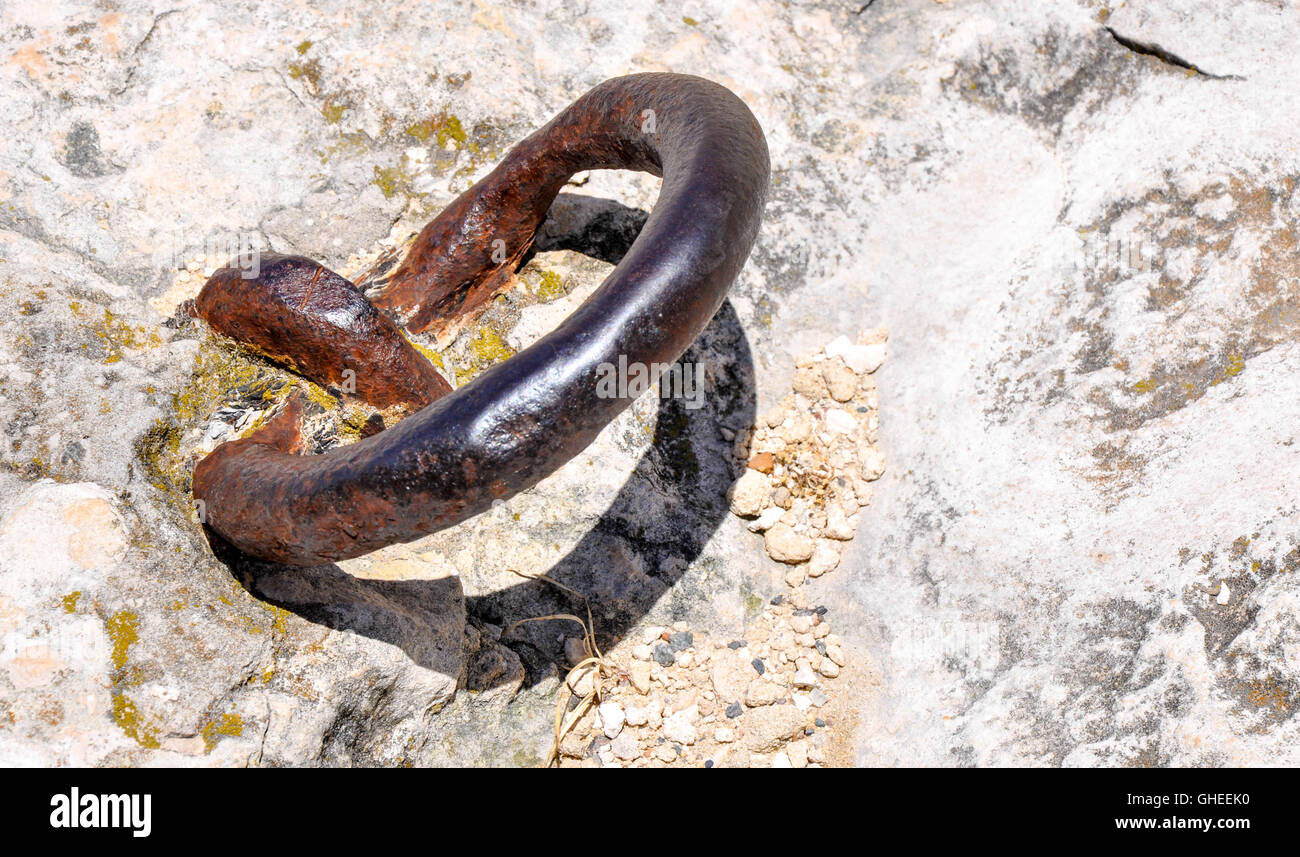 Rusty per impieghi pesanti bullone a occhio e l'anello di acciaio forgiato incorporato nella roccia calcarea. Foto Stock