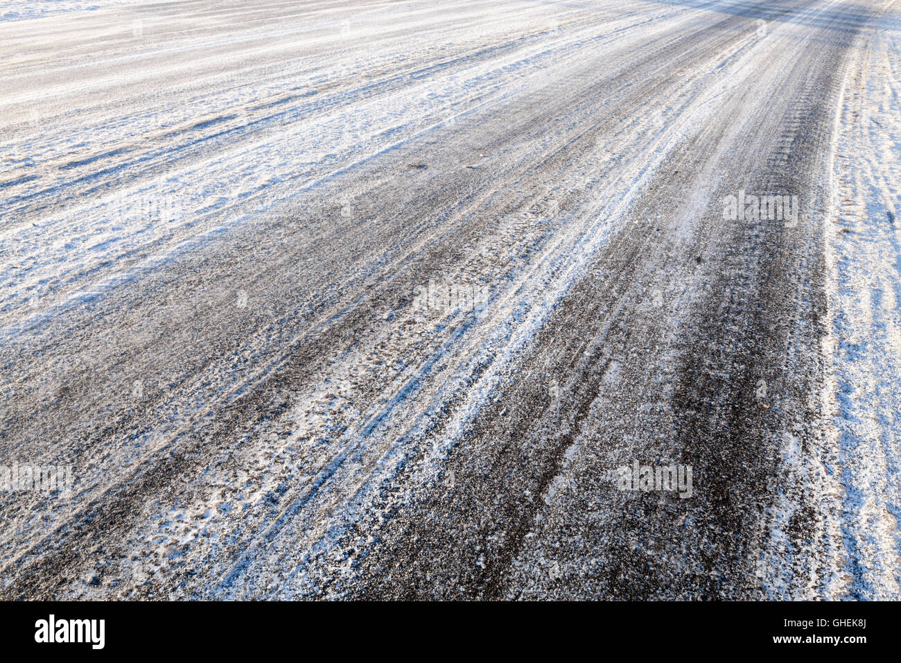 Strada ghiacciata. Tracce di pneumatici a sinistra in presenza di neve e ghiaccio sulla strada in inverno, England, Regno Unito Foto Stock