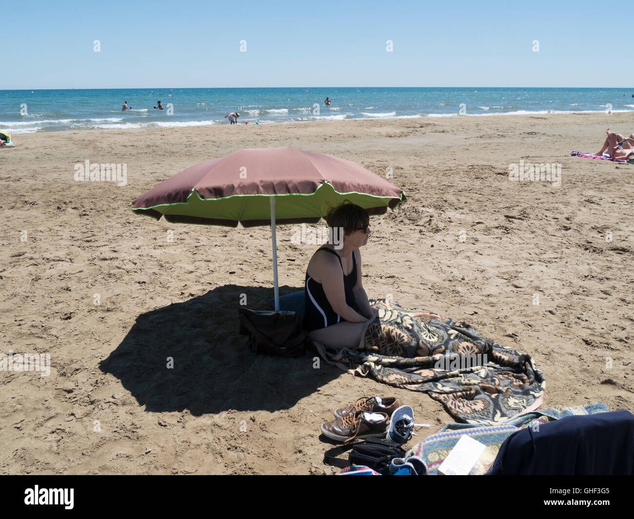 Una donna shelters fro il sole sotto un'ombra su una spiaggia di Gruissan sul Languedoc costa Mediterranea Foto Stock