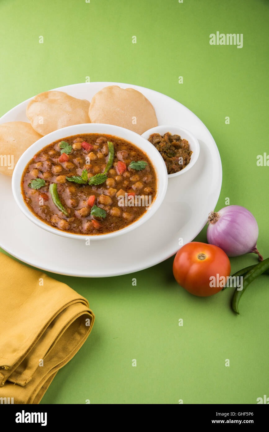 Piccante di ceci noto anche come Chola Masala o Chana Masala o Chole servita con fried puri, sottaceti e insalata verde Foto Stock