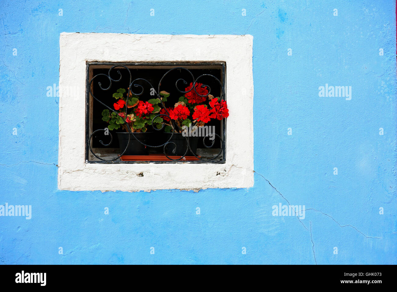 Bellissimo balcone fiorito con una finestra in casa e molti vasi di fiori Foto Stock