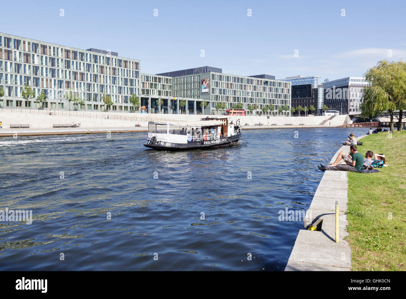 Le imbarcazioni turistiche sul fiume Sprea e persone rilassante dal lato nel distretto governativo di Berlino, Germania Foto Stock