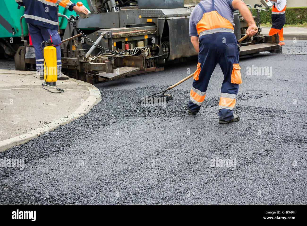 Lavoratori su asfaltatura lastricatore macchina durante la strada lavori di riparazione Foto Stock
