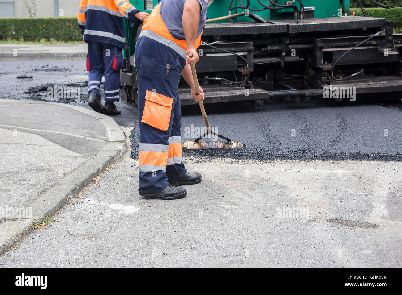 Lavoratori su asfaltatura lastricatore macchina durante la strada lavori di riparazione Foto Stock