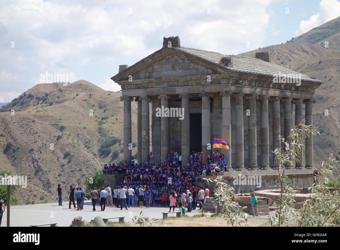 Garni tempio greco-romano c125 ad Armenia con ammassato ranghi della scuola i bambini sui gradini e armeno battenti bandiera Foto Stock