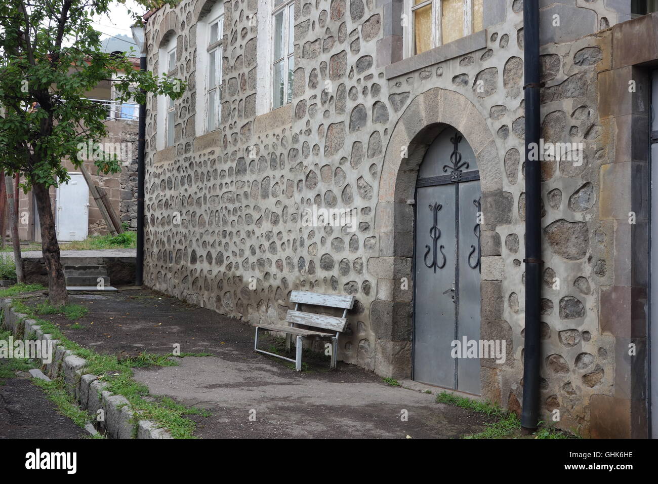 Goris Armenia sedile sul marciapiede esterno principale porta doppia in casa e giardino di puntamento pesanti intorno alla pietra di basalto Foto Stock