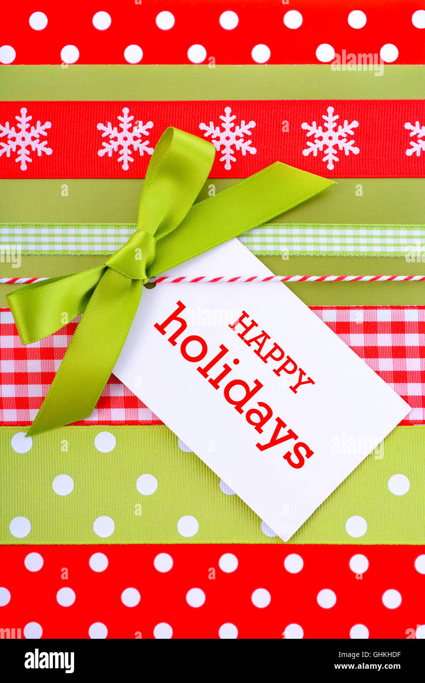 Natale moderno holiday saluto con sfondo rosso brillante e verde avocado confezione regalo con nastri multipli e dono tag. Foto Stock