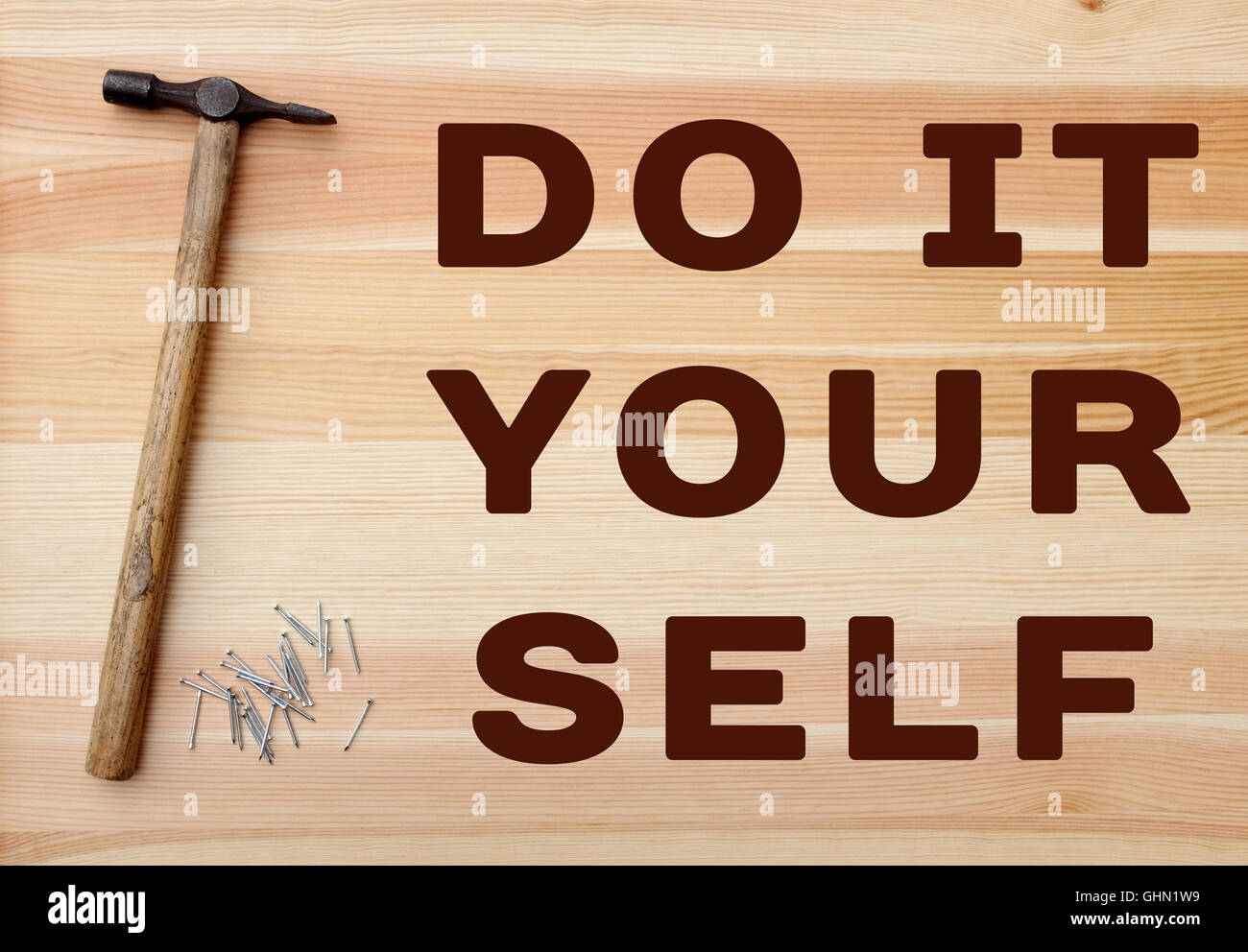 Il martello e il pannello di metallo perni con Do it yourself concetto scritto su uno sfondo di legno Foto Stock
