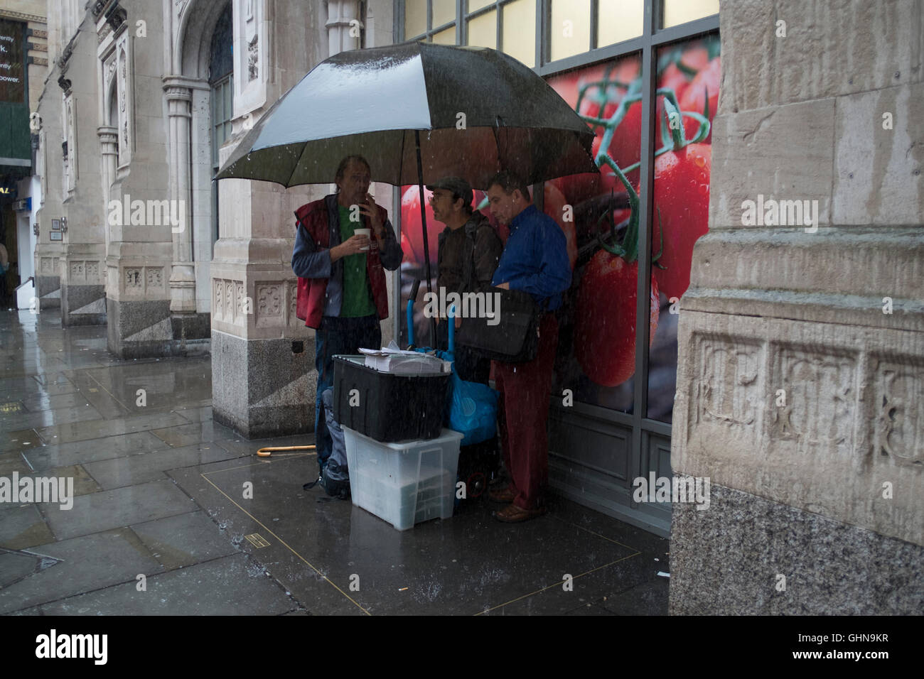 Le persone che eseguono per coprire o il ricovero sotto gli ombrelloni street scene in heavy rain su Bishopsgate nella City di Londra, Inghilterra, Regno Unito. Foto Stock