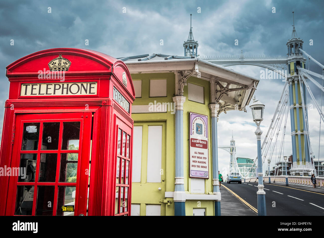 Un chiosco telefonico rosso di Londra su Albert Bridge, Chelsea, Londra, Inghilterra, Regno Unito Foto Stock