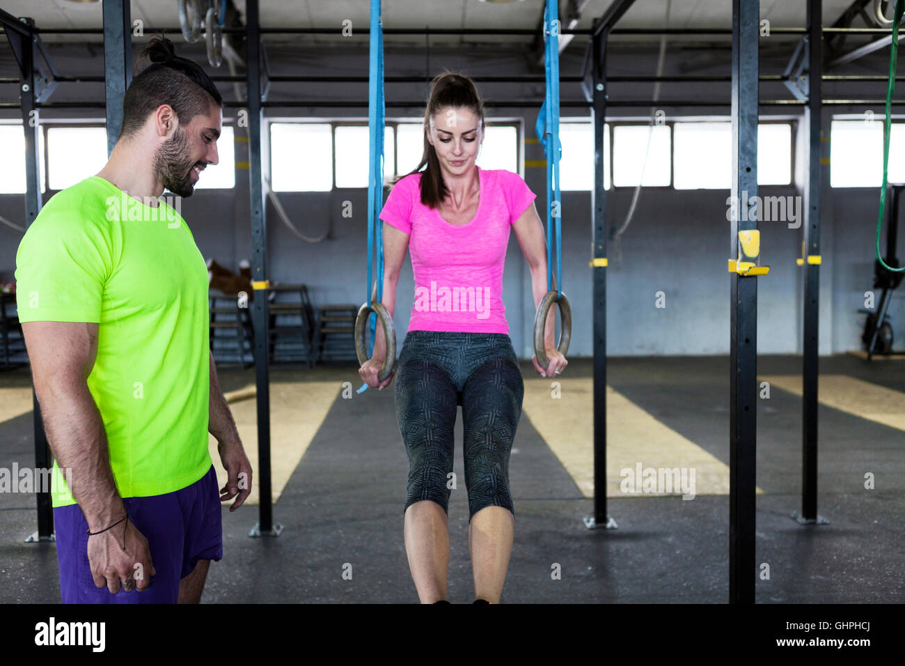Donna palestra facendo esercizio sugli anelli in palestra Foto Stock