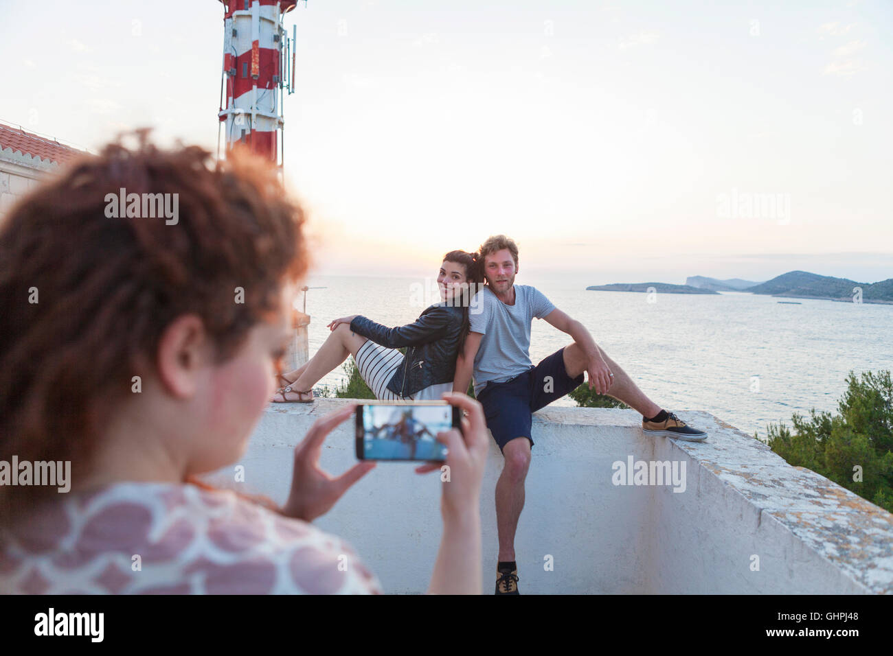 Giovane donna di scattare una foto di amici in riva al mare Foto Stock