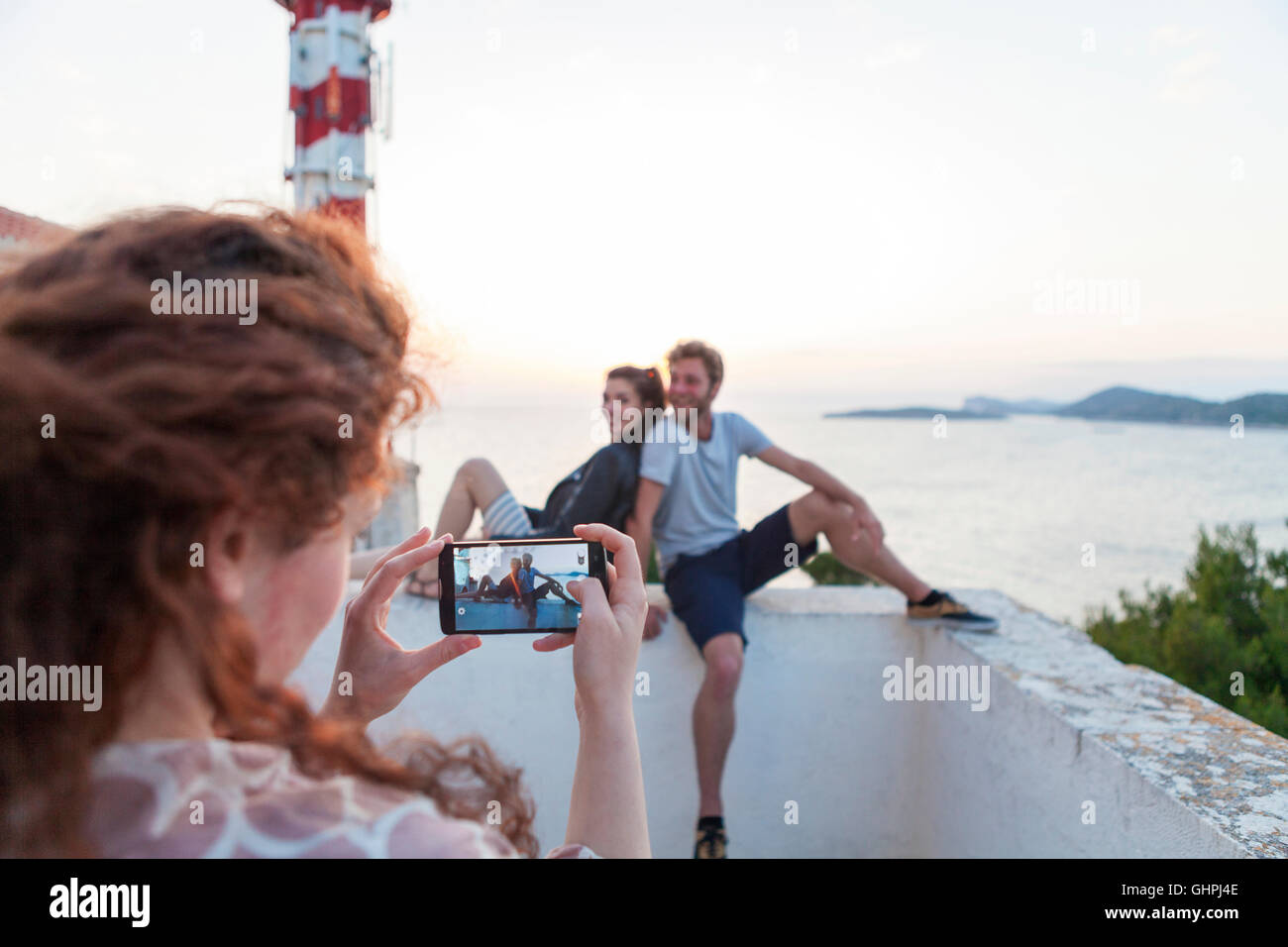 Giovane donna di scattare una foto di amici in riva al mare Foto Stock