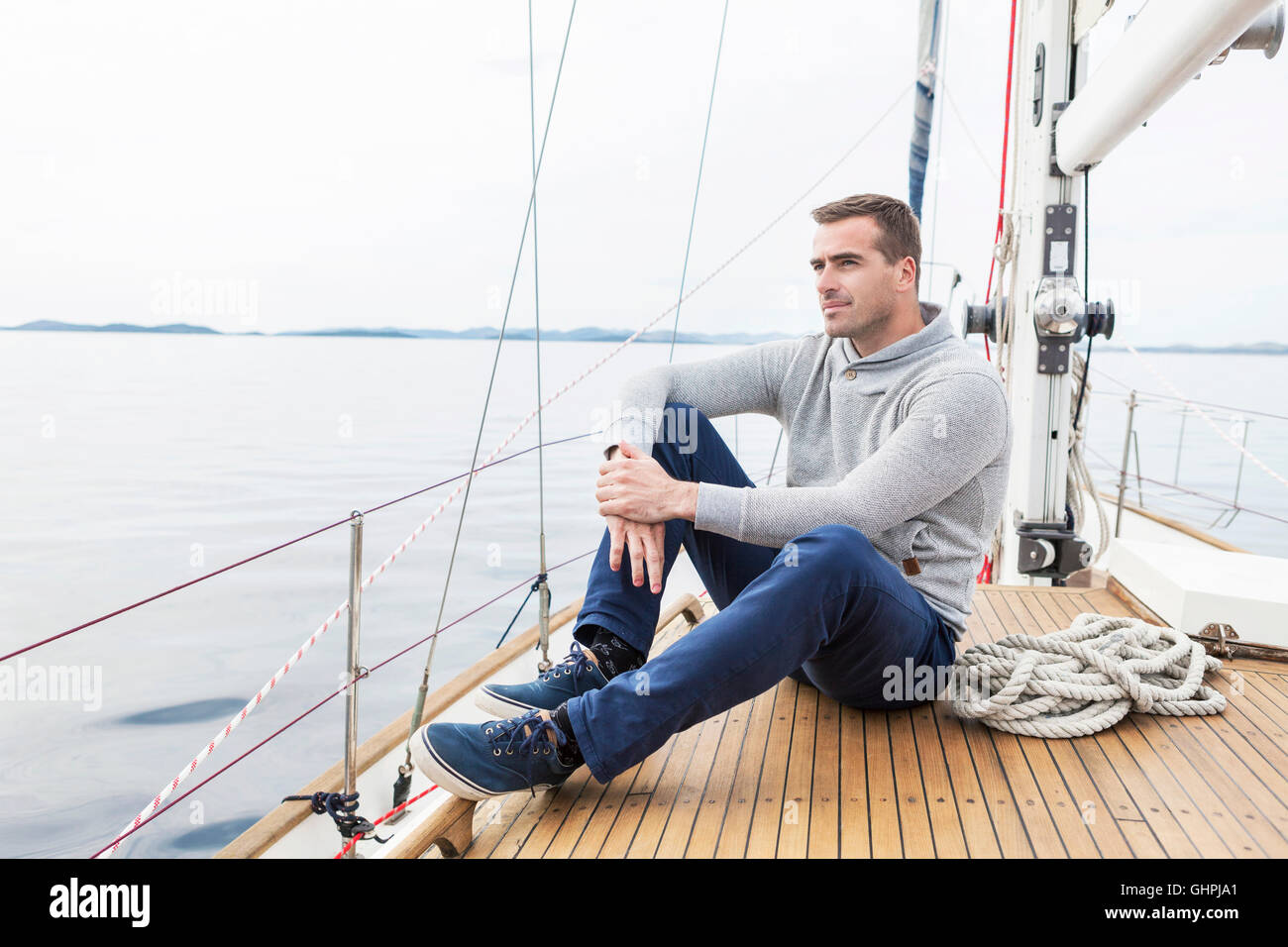 Uomo si siede sulla coperta della barca di yacht sogno ad occhi aperti Foto Stock