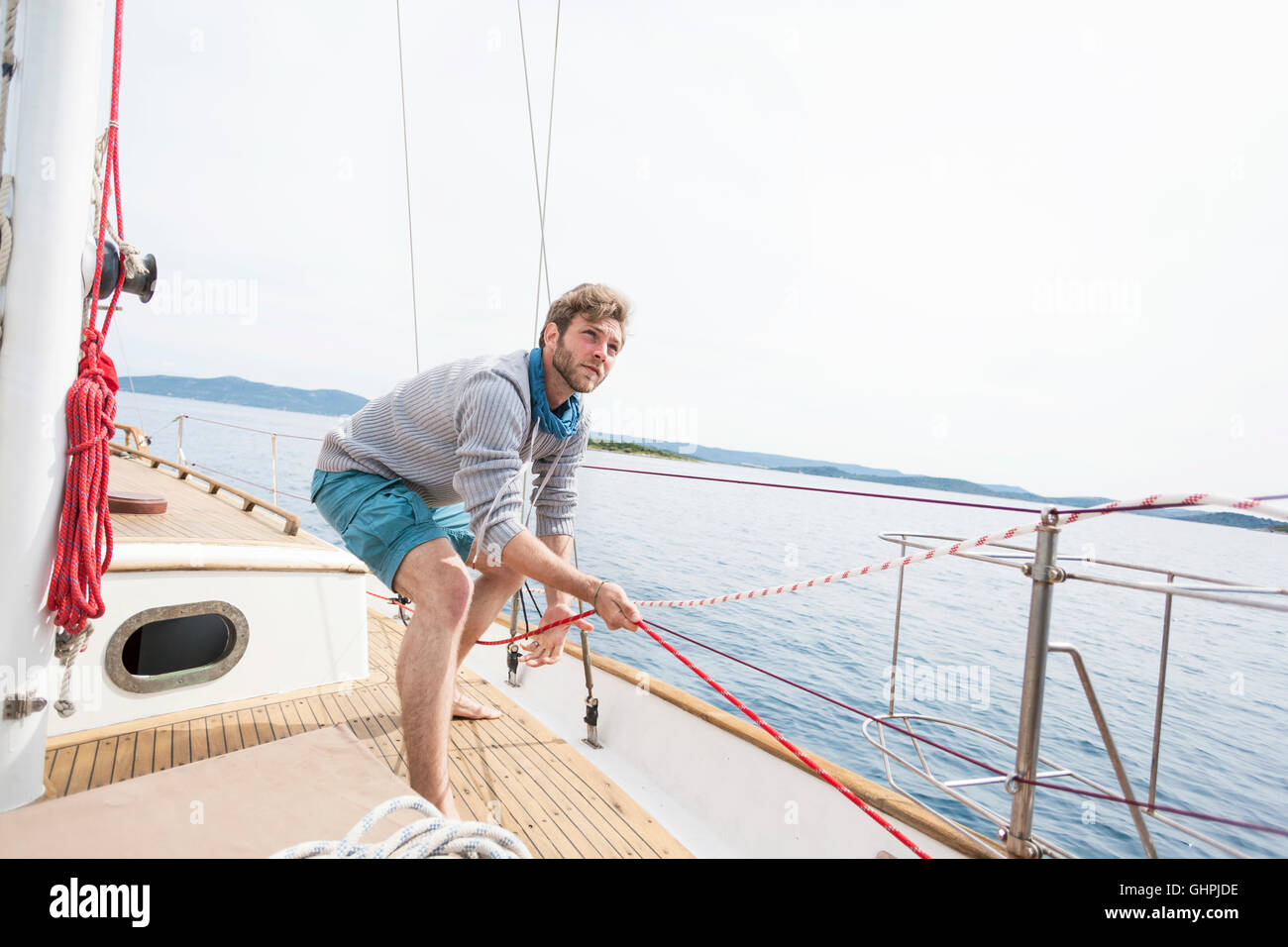 L'uomo tirando la corda sulla barca a vela Foto Stock