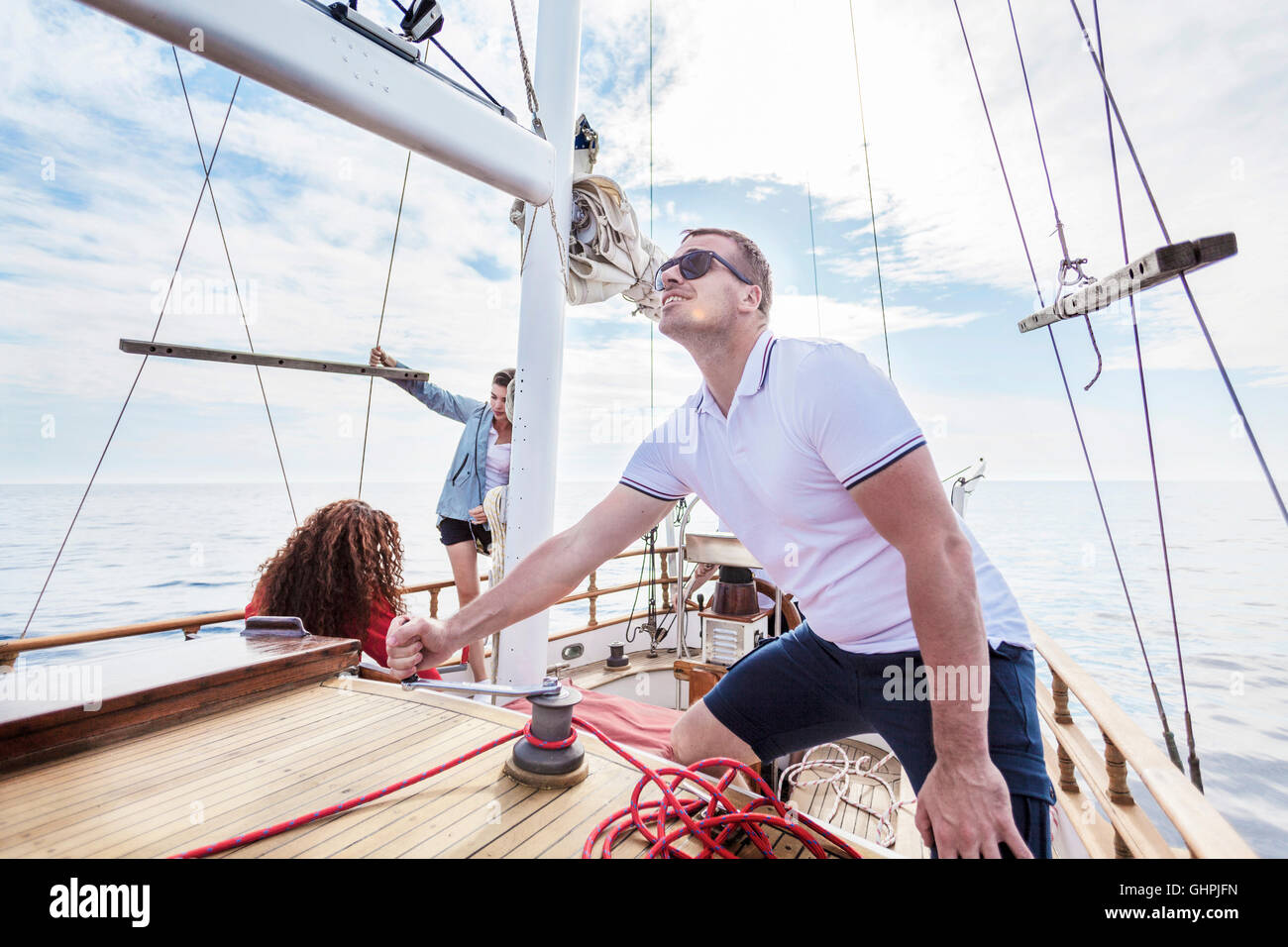 Uomo corda di avvolgimento con fune del verricello in barca a vela Foto Stock