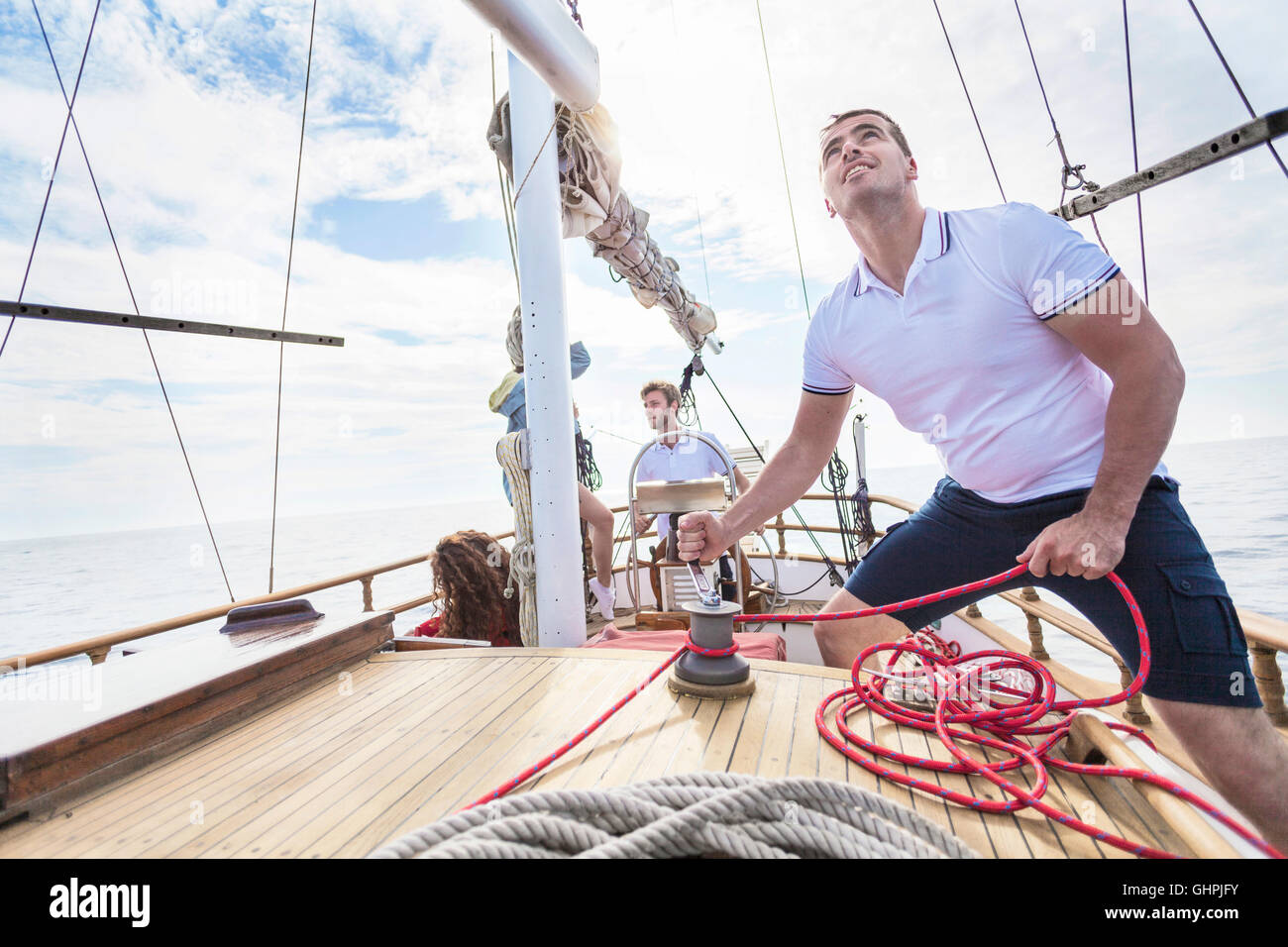 Uomo corda di avvolgimento con fune del verricello in barca a vela Foto Stock