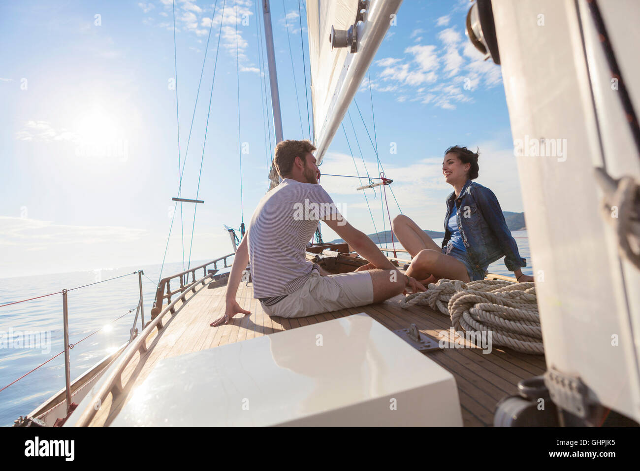 Coppia giovane seduto faccia a faccia sulla barca a vela Foto Stock