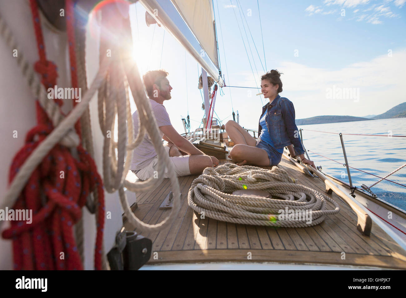 Coppia giovane seduto faccia a faccia sulla barca a vela Foto Stock