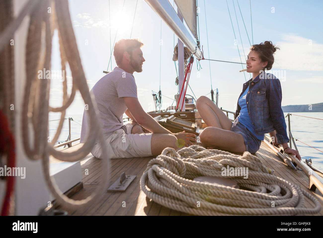 Coppia giovane seduto faccia a faccia sulla barca a vela Foto Stock