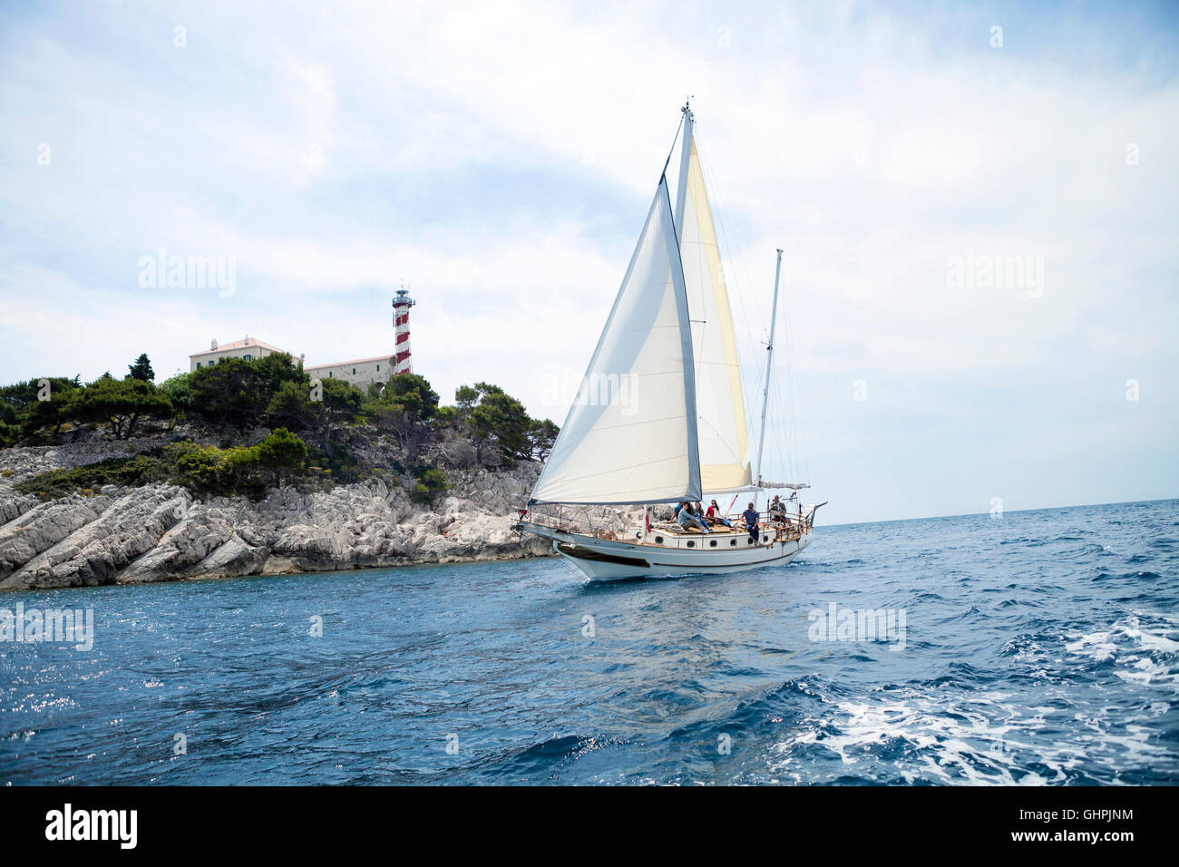 Nave a vela con il faro in background Foto Stock