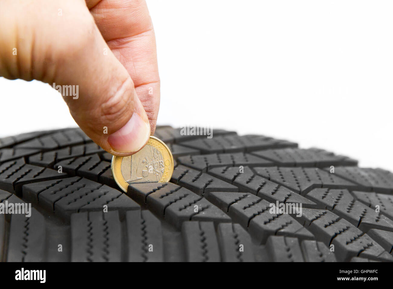 Uomo di controllo del profilo del pneumatico con una moneta Foto Stock