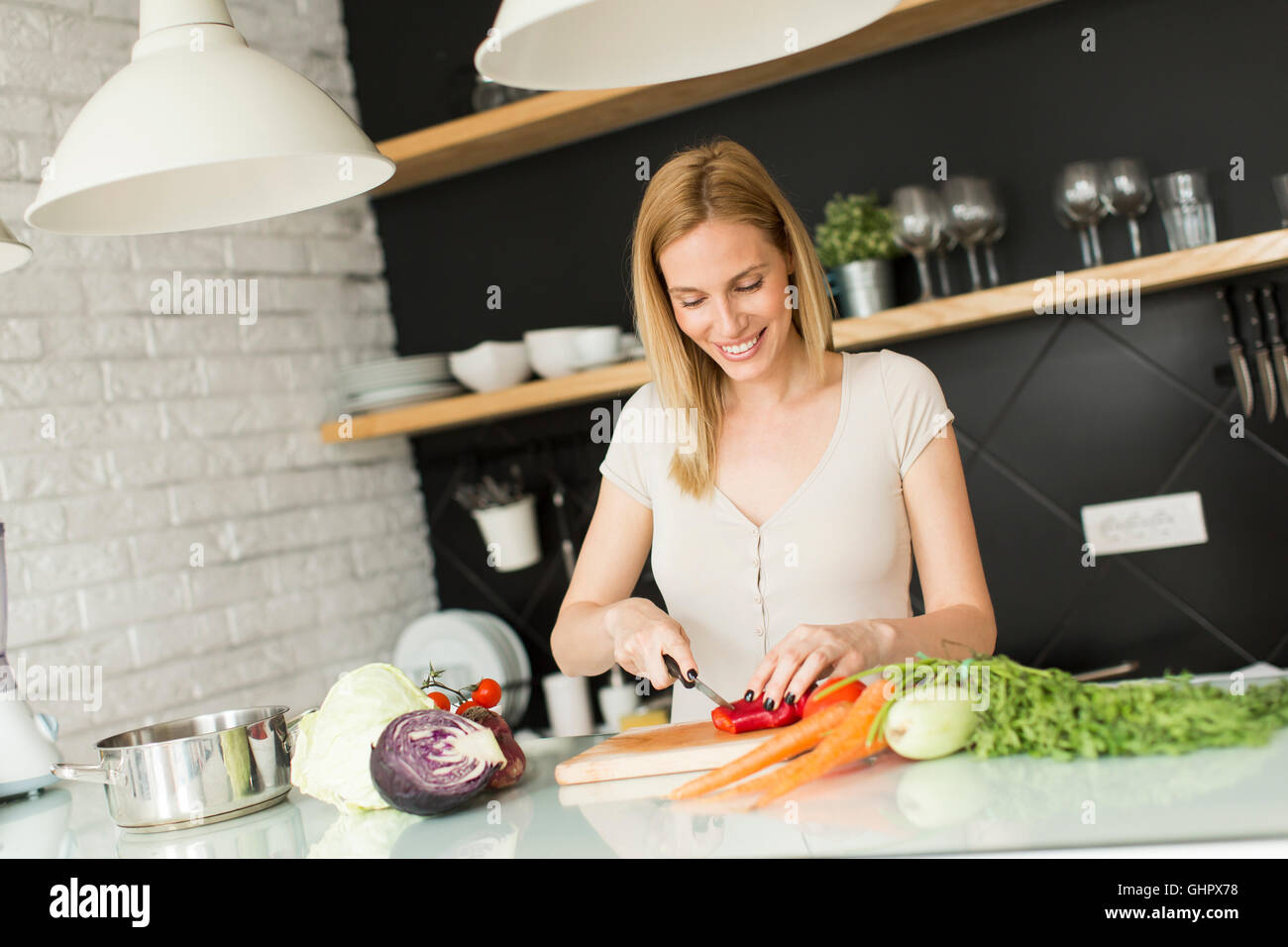 Giovane donna preparare frullati in cucina Foto Stock