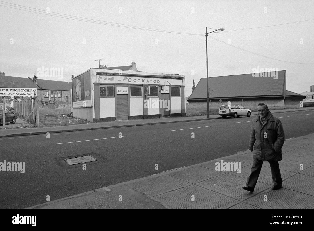 Un uomo che cammina al di fuori della Cacatua Public House, Pollockshaws nel southside di Glasgow nel 1991. Foto Stock