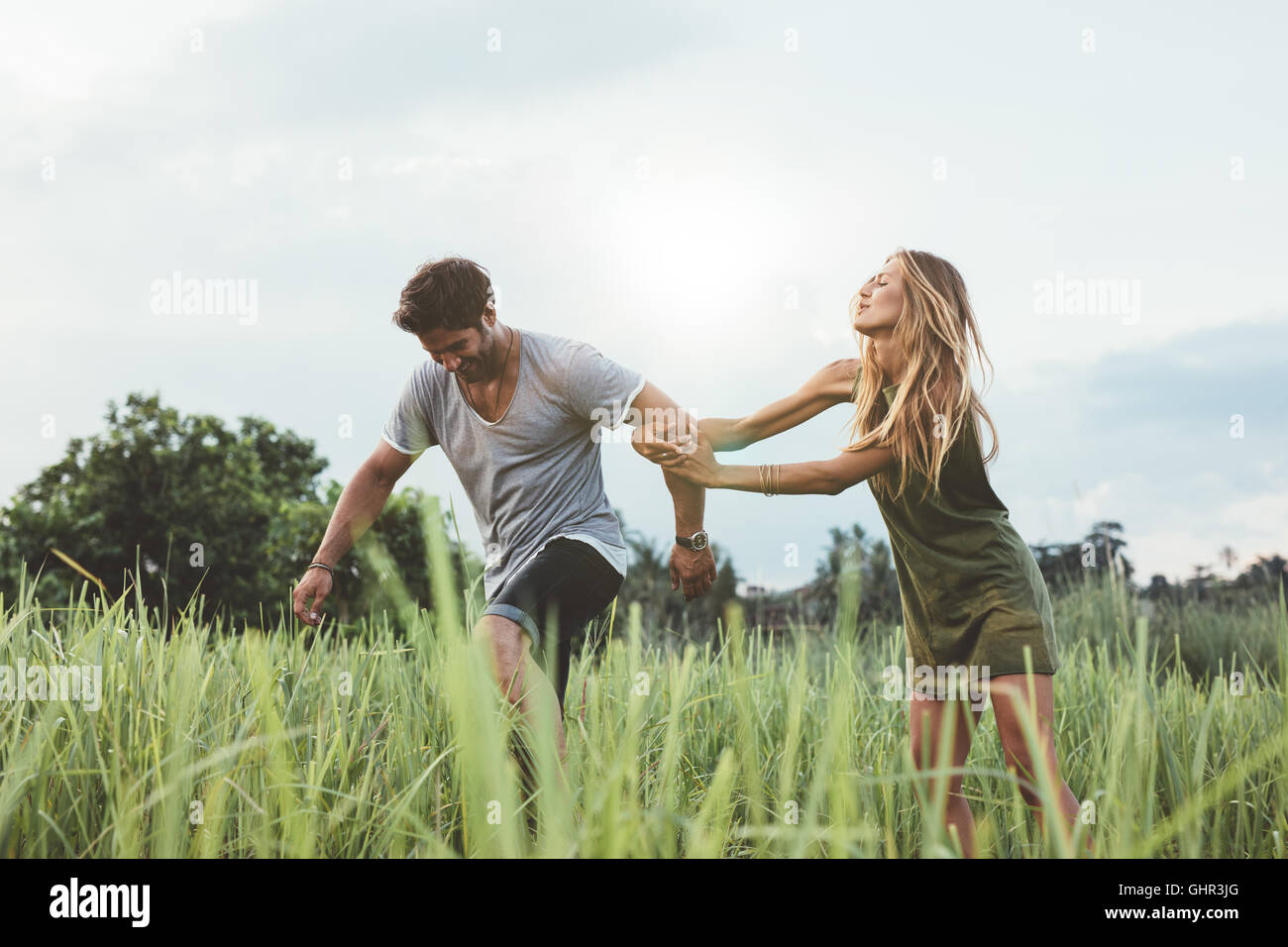 Colpo all'aperto di coppia giovane nel campo di erba. L uomo e la donna godendo una giornata in natura. Divertirsi sulla loro vacanza. Foto Stock