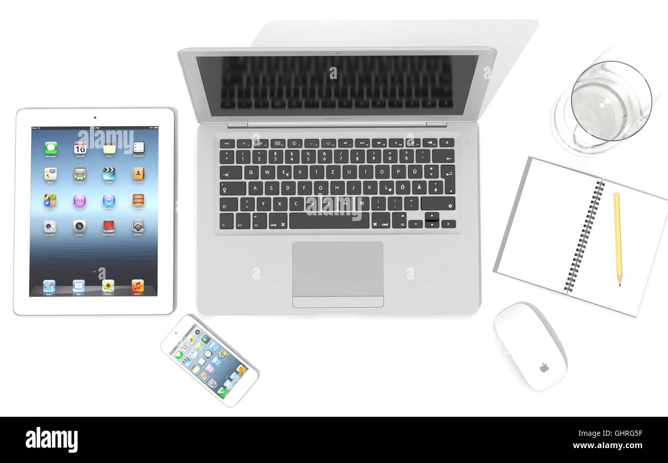IPad, iPhone 5, Macbook Air e Apple magic mouse su una scrivania con un bicchiere di acqua e una nota di libro e matita Foto Stock