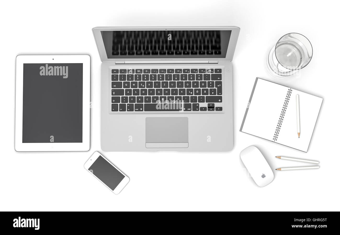IPad, iPhone 5, Macbook Air e Apple magic mouse su una scrivania con un bicchiere di acqua e una nota di libri e matite Foto Stock