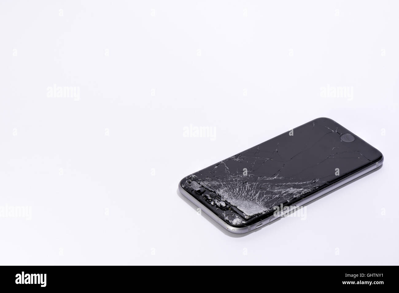 Un telefono cellulare con schermo rotto su sfondo bianco Foto Stock