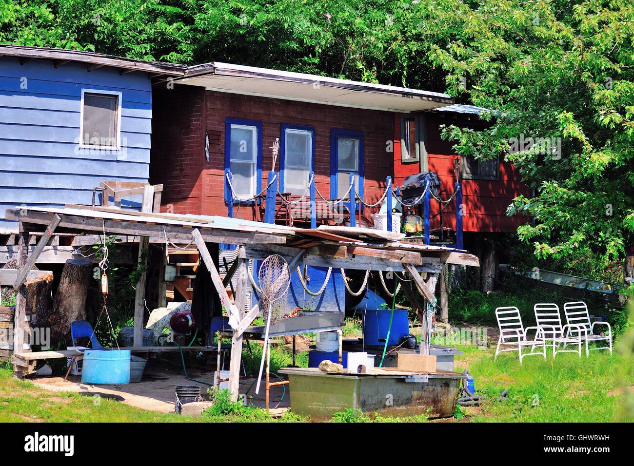 Sedie allineate per fornire una vista e reti da pesca appesa al rifugio protetto a queste case siedono lungo il fiume Mississippi. Gutenberg, Iowa, USA. Foto Stock