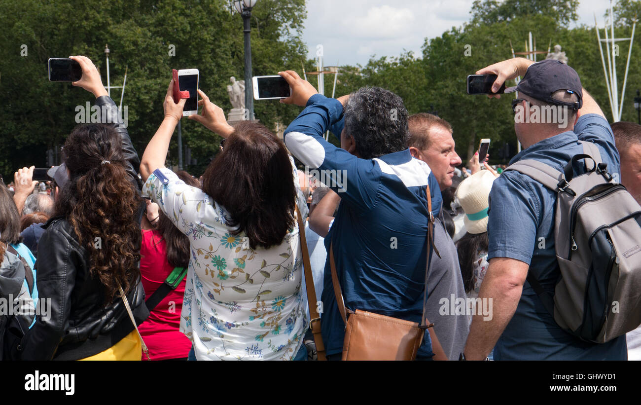 I turisti tenere i loro telefoni cellulari sopra le loro teste a prendere una foto sopra la folla al cambio della guardia a Londra, Inghilterra Foto Stock