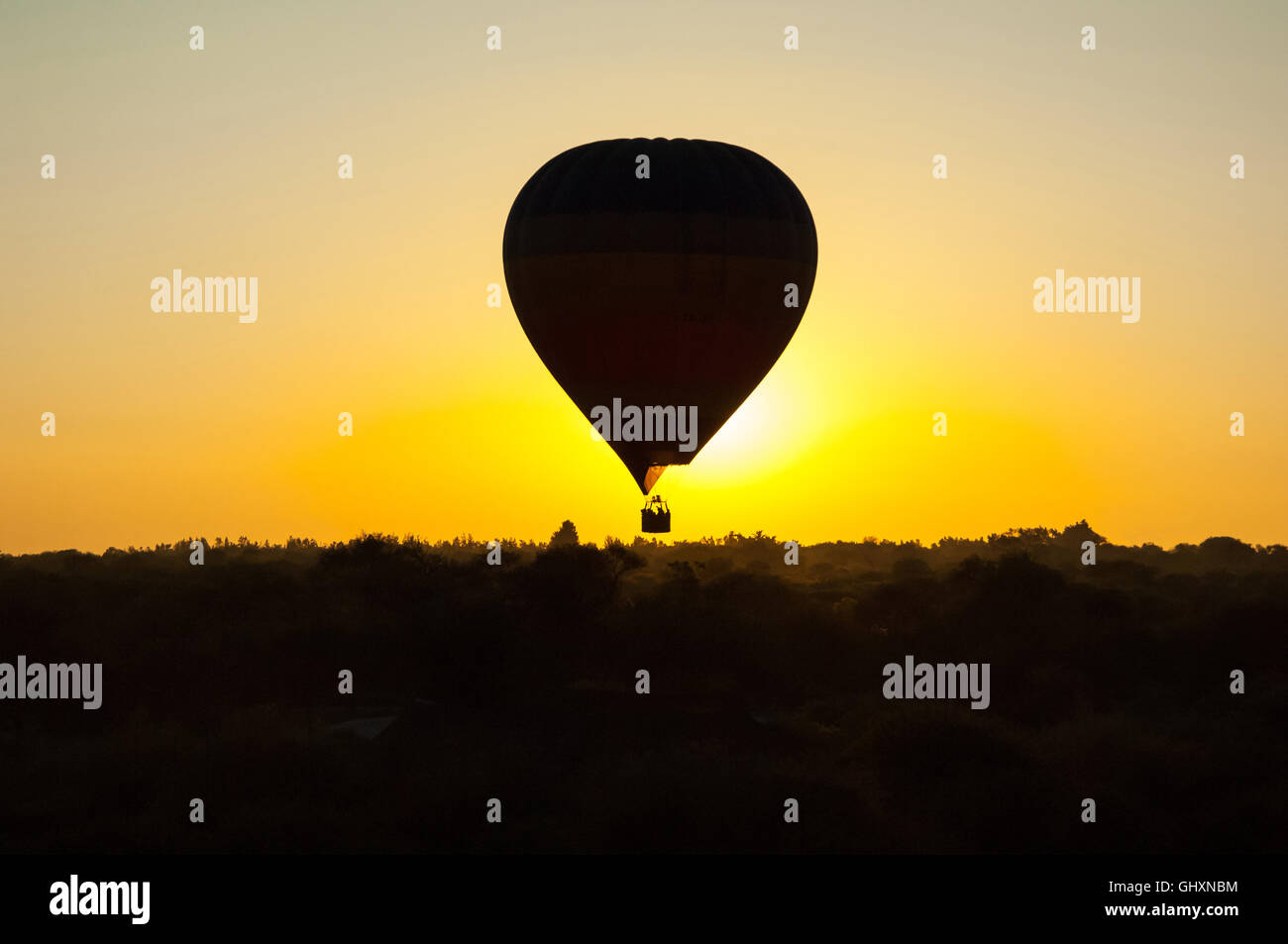 Silhouette di una mongolfiera nel cielo senza nuvole al tramonto su misty pianura africana Foto Stock