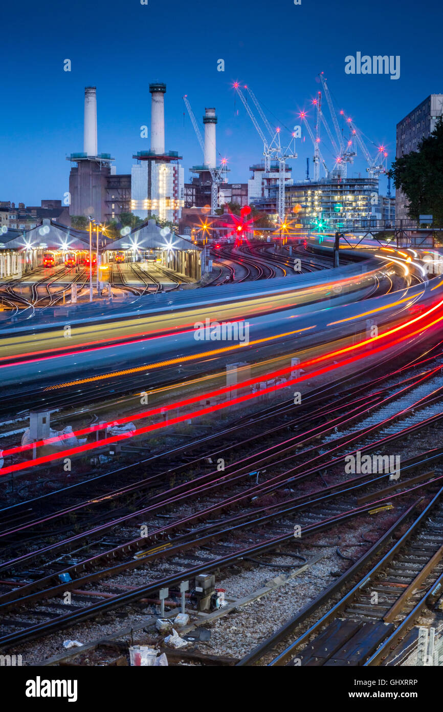 I treni partono sentieri di luce che si muovono oltre il sito in costruzione di Battersea Power Station Foto Stock