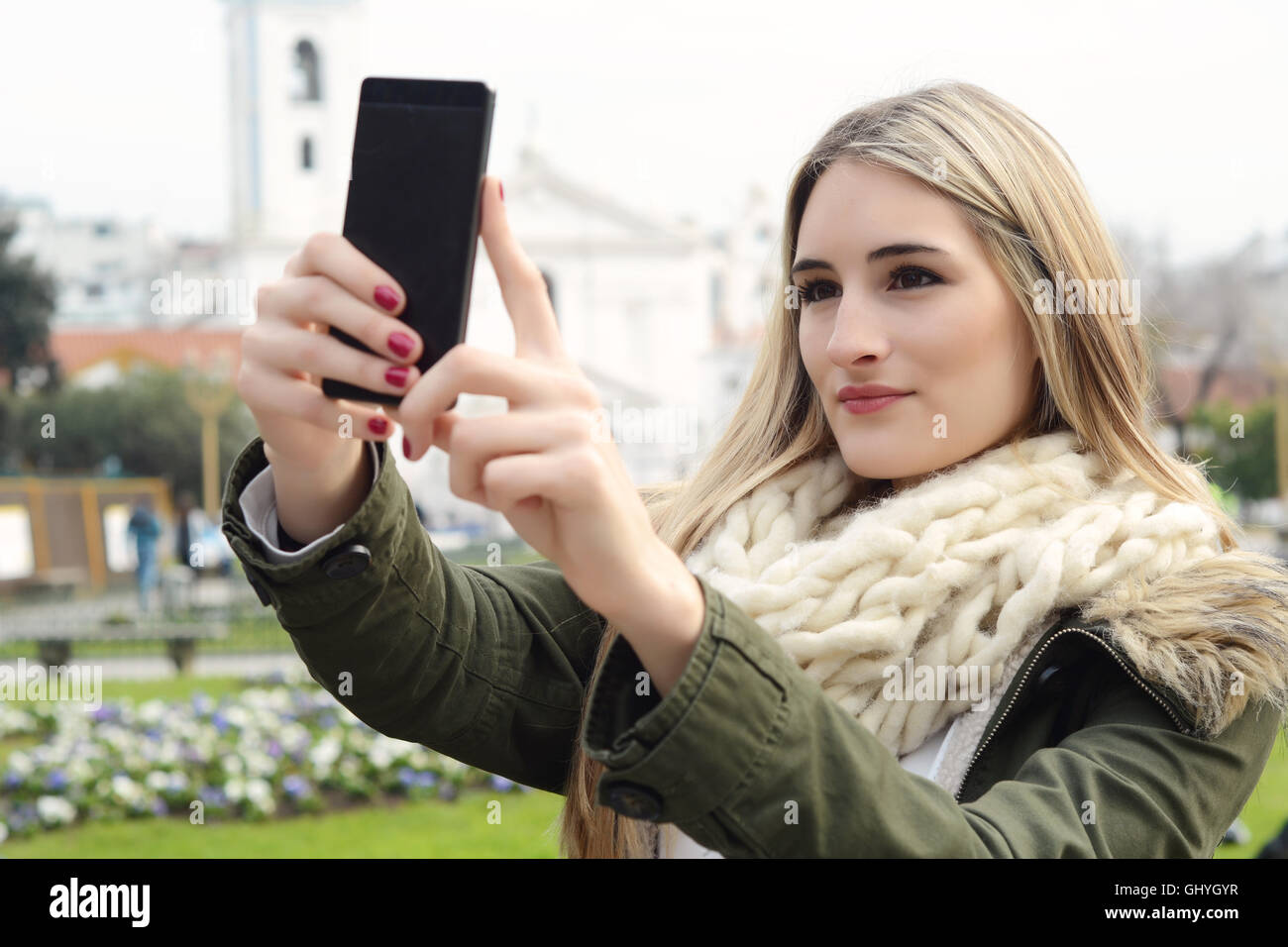 Ritratto di una giovane donna bellissima tenendo selfie con il suo smartphone. All'esterno. Foto Stock