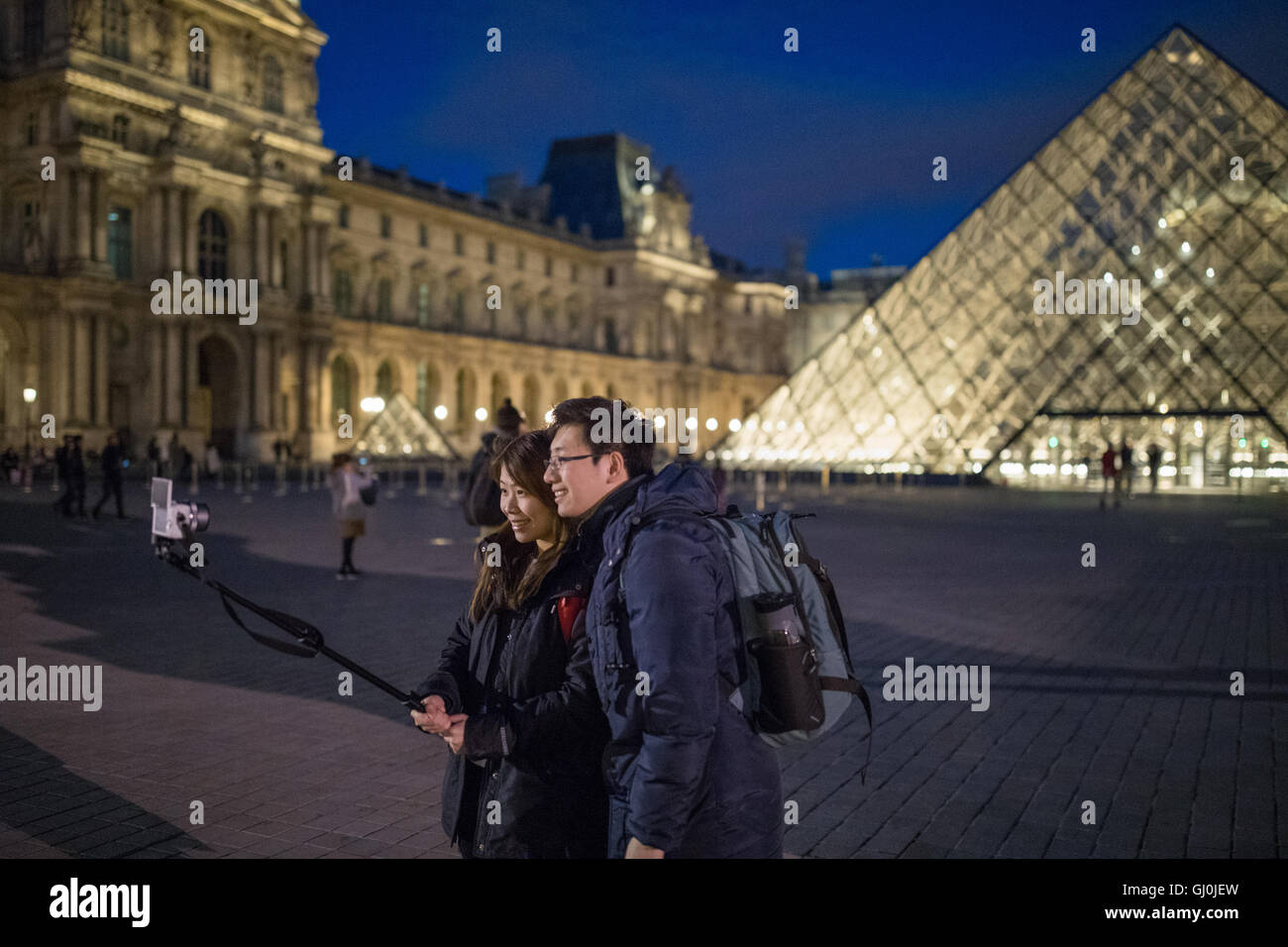 I turisti prendendo un Selfie presso il Palais du Louvre al crepuscolo, Parigi, Francia Foto Stock