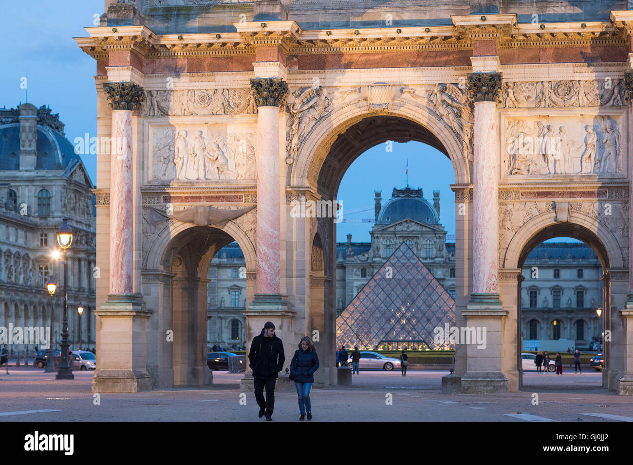 Un paio di passeggiare dall'Arc de triomphe du Carrousel & Palais du Louvre al crepuscolo, Parigi, Francia Foto Stock