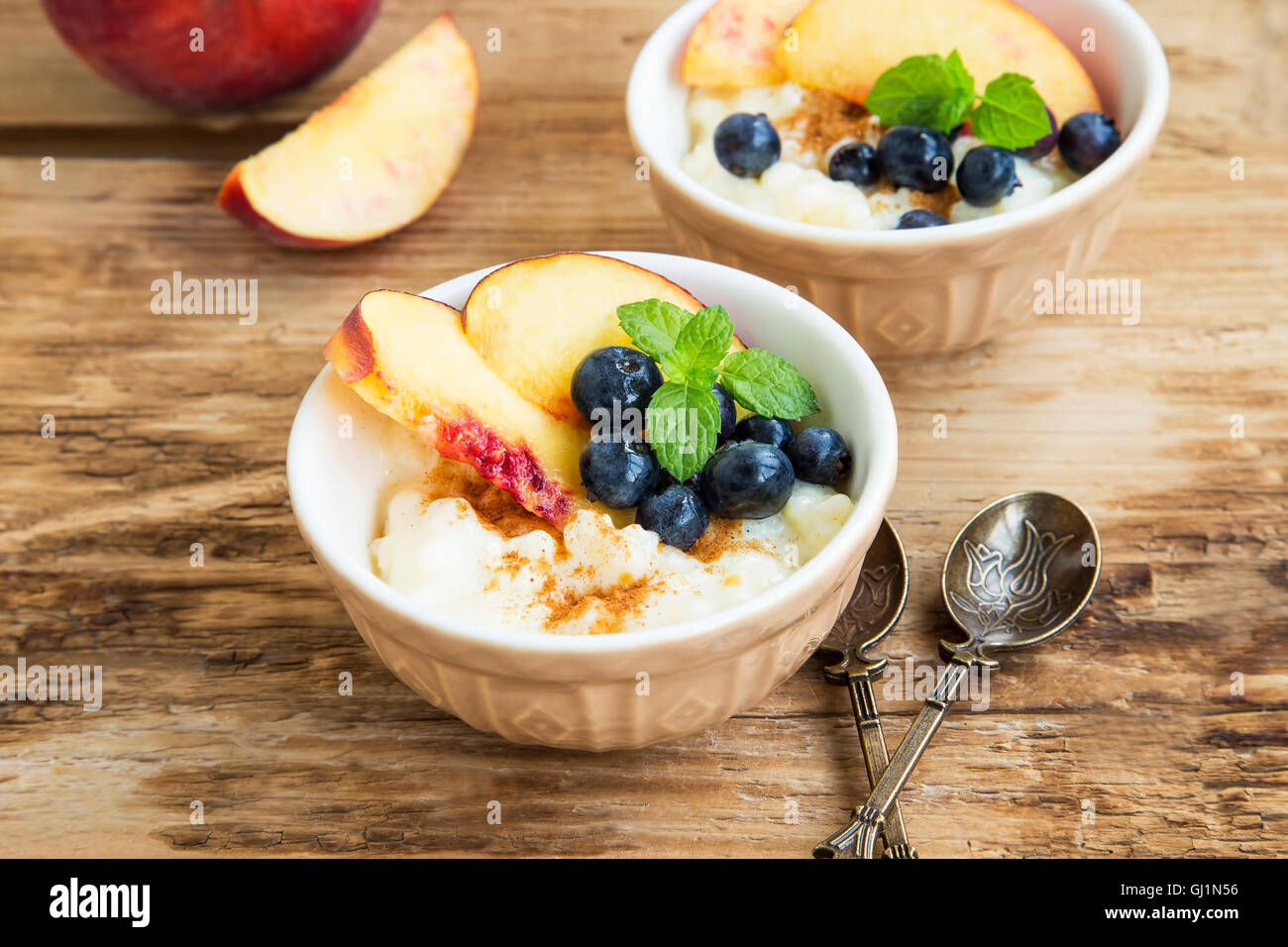 Budino di riso con cannella, i mirtilli, le pesche e le foglie di menta fresca Foto Stock