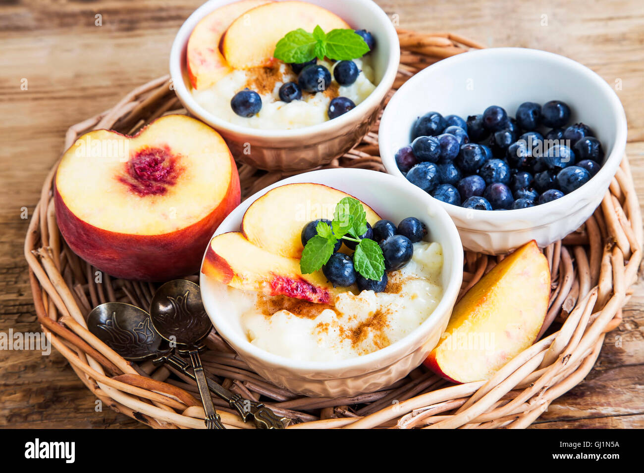 Budino di riso con cannella, i mirtilli, le pesche e le foglie di menta fresca Foto Stock