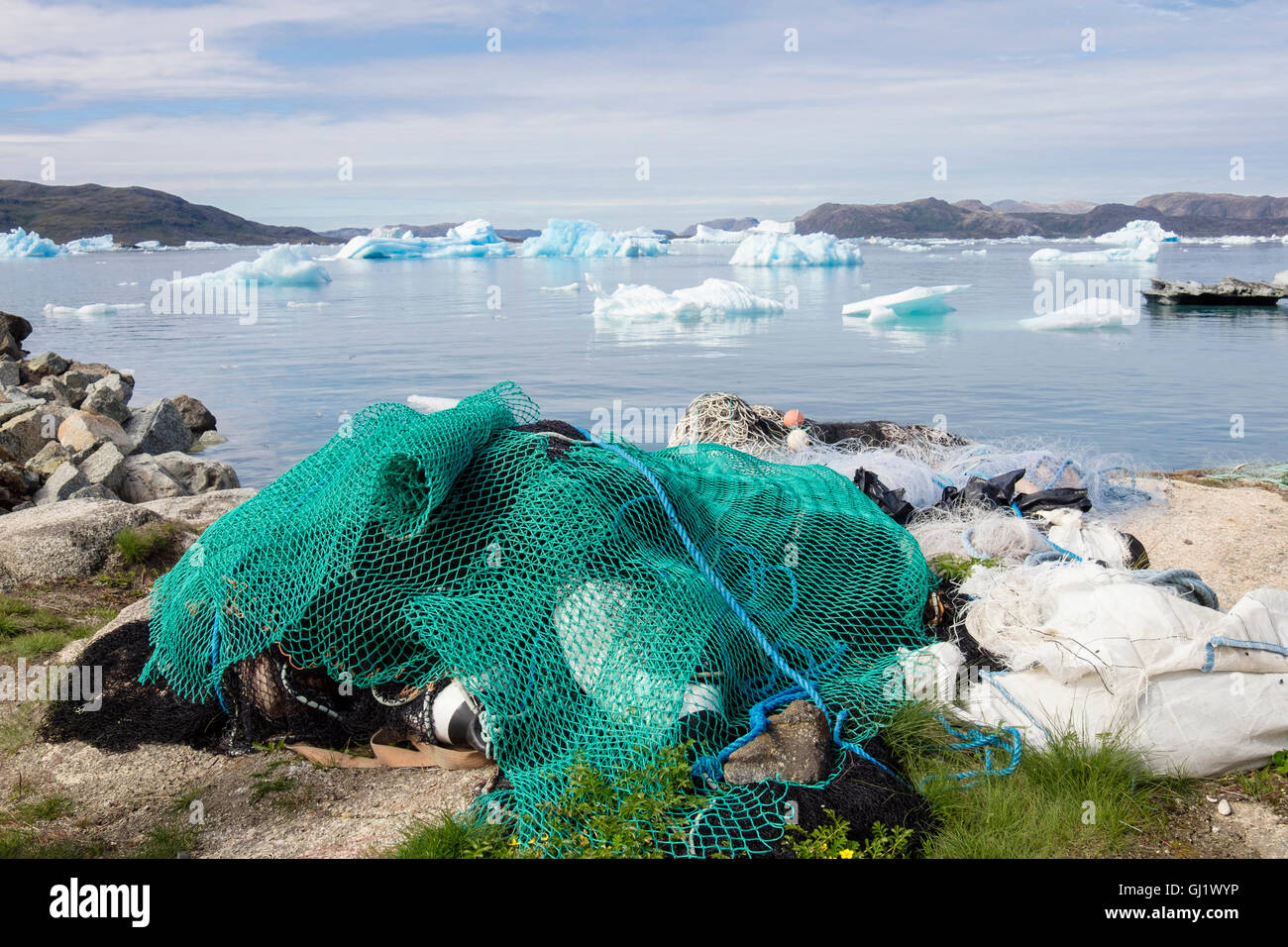 Inuit reti da pesca sulla spiaggia nel porto di Qajaq con gli iceberg offshore nel fiordo Tunulliarfik in estate 2016. Narsaq Kujalleq Groenlandia meridionale Foto Stock