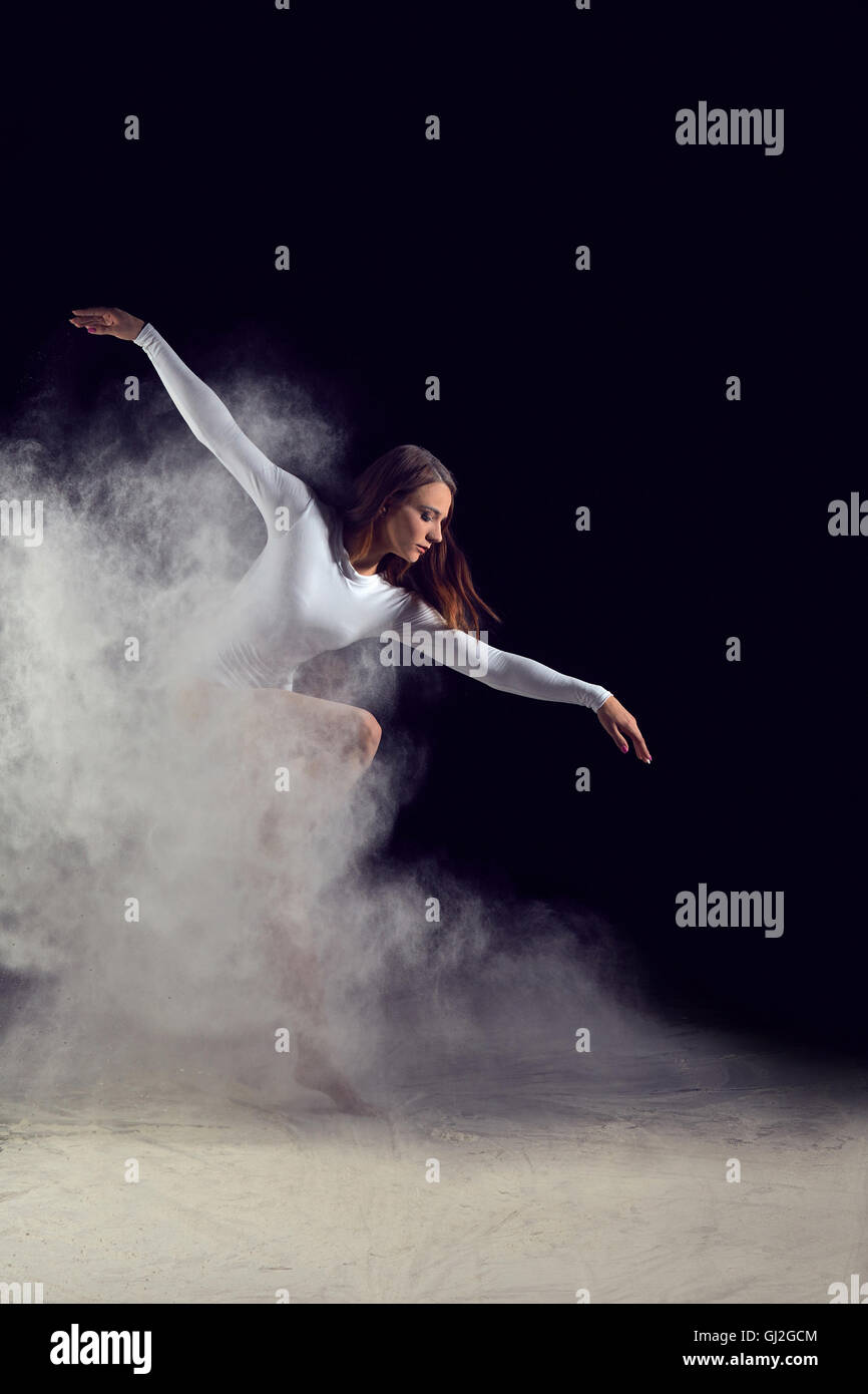 Ballerina ballando con la farina su uno sfondo nero Foto Stock