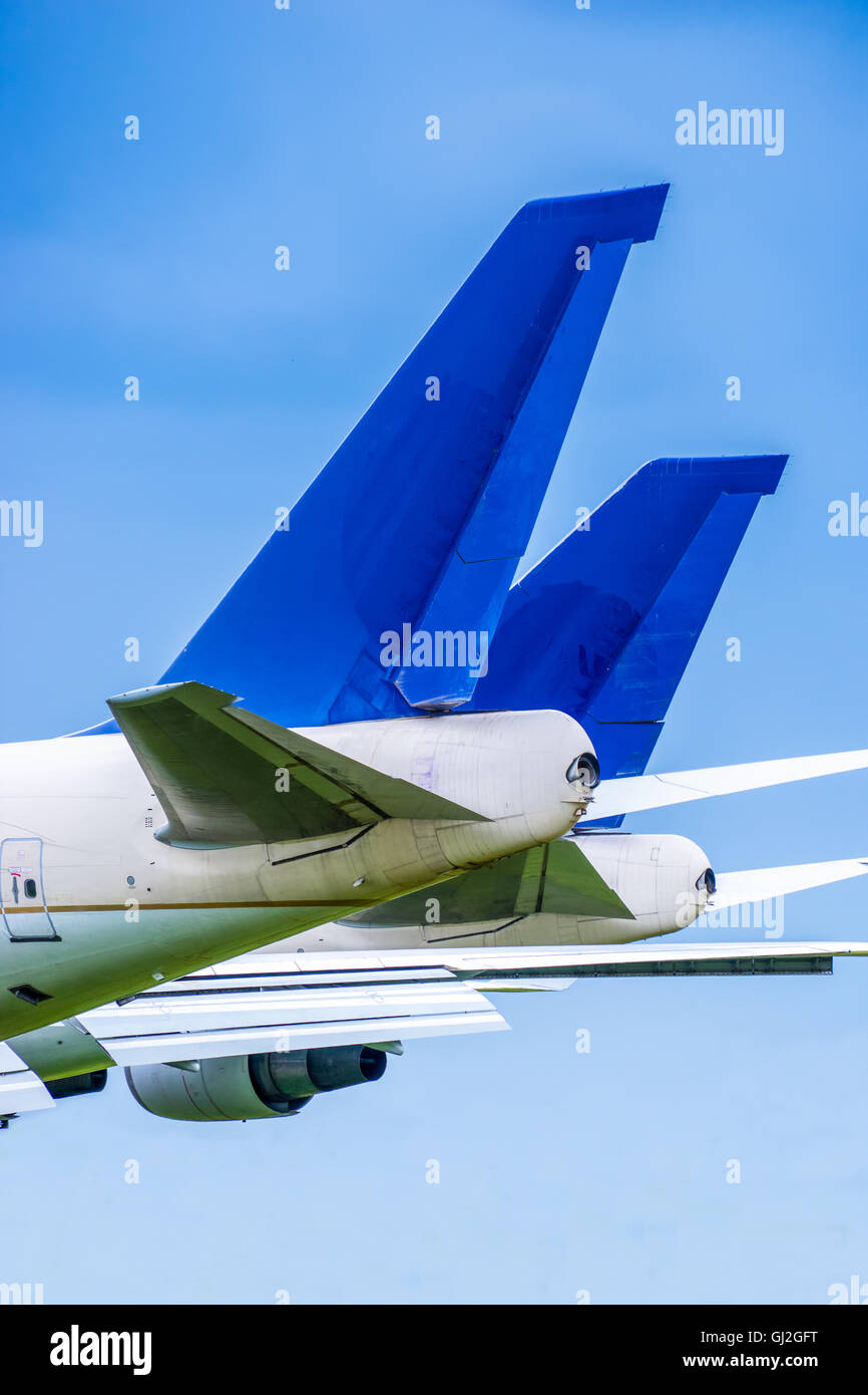Due jet di linea blu piani di coda parcheggiato a fianco a fianco contro un cielo blu Foto Stock